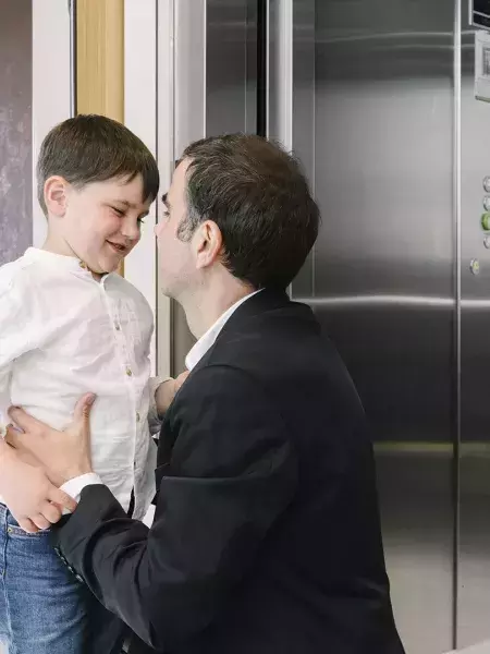 Pai e filho no patamar junto ao elevador Orona